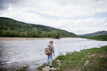 Man tourist with a backpack travels along the mountain river. Copy spaseの写真素材
