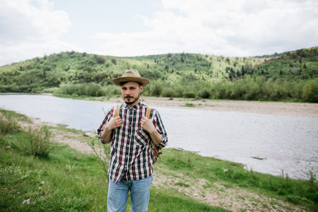 Portrait of a young hipster in a hat traveling alone in the mountains. Travel conceptの写真素材