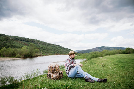 The tourist sat down to rest on the banks of a mountain river after a difficult and long hiking...