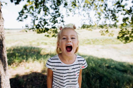 Little baby girl screaming in summer park outdoorsの写真素材