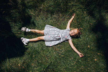 Happy child lying on the green grass in the park. Top viewの写真素材