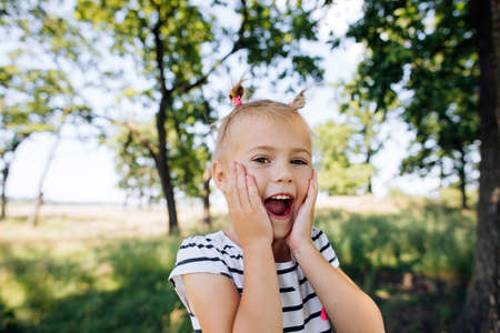 A child screams with happiness and surprise in a summer park outdoors. Happy momentsの写真素材
