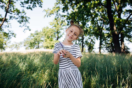 Girl in a striped dress with a flower in his hands looks at the camera. Happy summerの写真素材