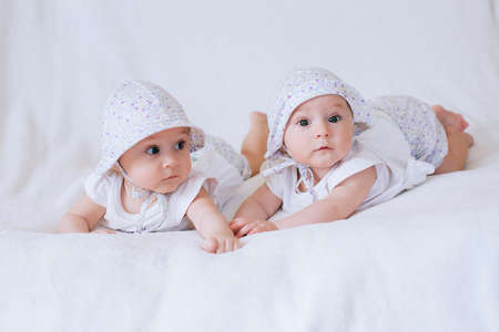 Happy twin sisters playing at home on a white backgroundの写真素材