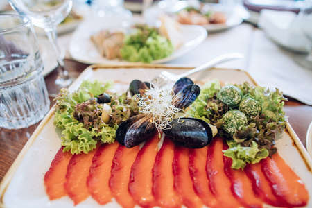 Dish of salmon and mussels on a white plate on the table in a restaurant. Wedding dinnerの写真素材