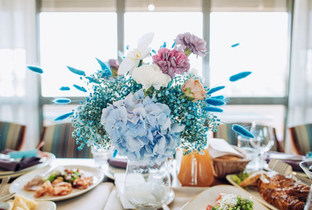 Blue bouquet of fresh flowers on a festive table for dinner. Romantic decor of tables in the...