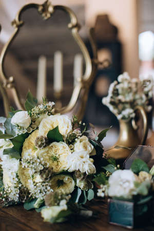 Elegant wedding bouquet of the bride of white roses on a wooden table with a mirrorの写真素材