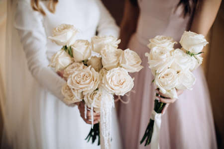 The bride and her friend are holding wedding bouquets of white rosesの写真素材