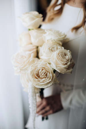 The bride holds a wedding bouquet of white rosesの写真素材