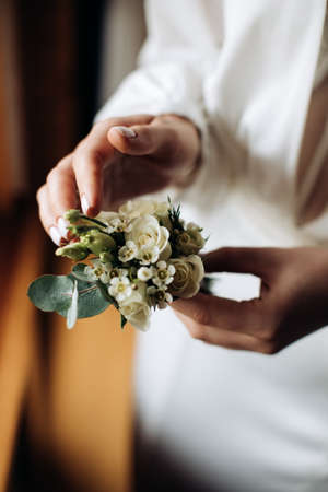 The bride holds a white boutonniere for the groom. wedding accessoriesの写真素材