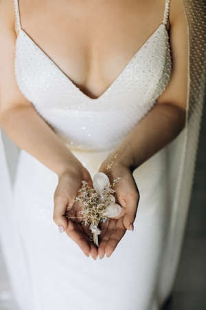 The bride holds a boutonniere for the groomの写真素材