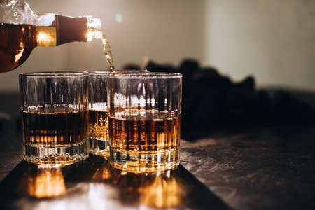 A man pours brandy into glasses at a restaurant at a partyの写真素材