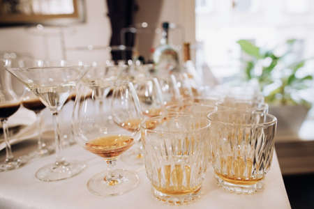 Glasses of whiskey, cognac, scotch, martini on table at wedding partyの写真素材
