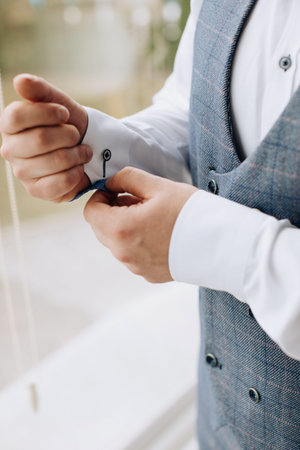 The groom puts on a shirt at the hotel. wedding morning