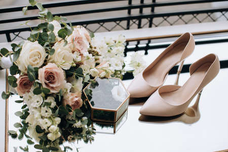 Beautiful wedding bouquet of beige and white roses and wedding shoesの写真素材