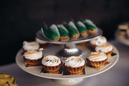 Cakes with cream on a plate on the dessert table. Sweet food at the partyの写真素材