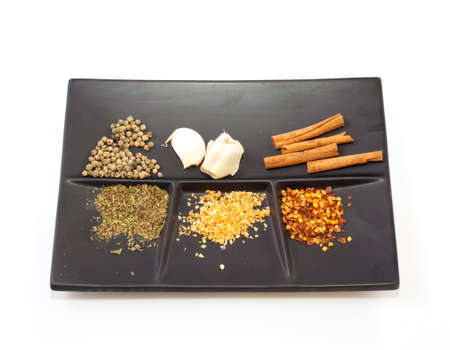 Spices on a black saucer on a white backgroundの写真素材