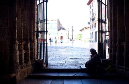 An old beggar next to the door of the churchの写真素材
