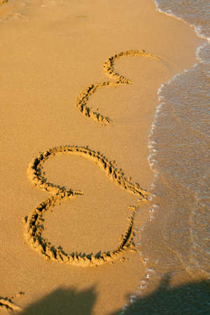 Drawing the Hearts in the beachの写真素材