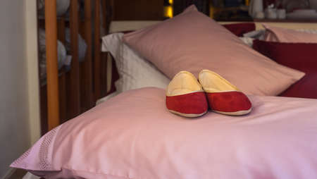 Red female slippers on the pink pillowの写真素材
