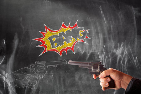 View of hand drawing of handguns vs real handgun on blackboard