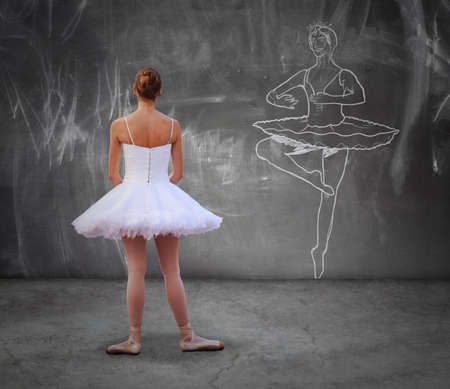 Young dancer girl looking a draft of classic dancer on the wall, aspiring to be like herの写真素材