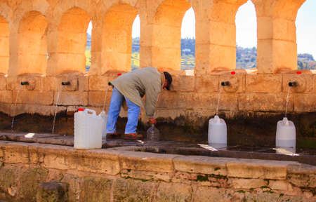 LEONFORTE, ITALY - JANUARY, 08: Man filling cans with fountain water on January 08, 2015の写真素材