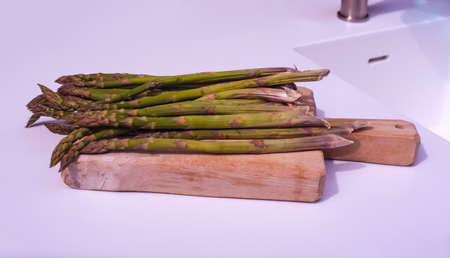 View of bunch of fresh asparagus on cutting board View of bunch of fresh asparagus on cutting board