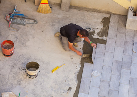 TRIESTE, ITALY - APRIL, 22: Worker Installing ceramic floor tiles on April 22, 2015のeditorial素材