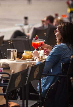 TRIESTE, ITALY - APRIL, 28: Girlfriens drinking a cocktail sitting in the outdoor coffee bar on April 28, 2016のeditorial素材
