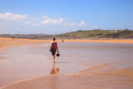 LIENCRES DUNES, SPAIN - AUGUST, 21: Woman walking in the water edge of the Liencres dunes nature reserve in the Cantabrian sea on August 21, 2016のeditorial素材