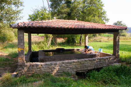 MELIDE, SPAIN - AUGUST, 14: A woman washes her clothes in the wash house on August 14, 2016のeditorial素材