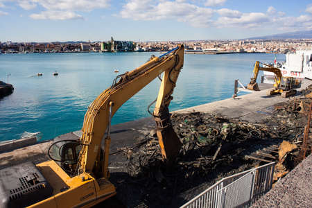 Cranes next to the piles of garbage and metal scrap in the Catania pier の写真素材