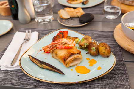 Close up of delicious roll fish with king prawn, peppers, potatoes, aubergines accompanied with...