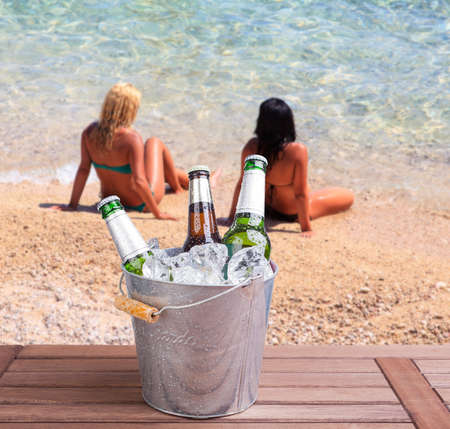Three unopened bottles of beer inside ice bucket on beach backgroundの写真素材
