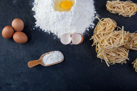 Italian homemade pasta called fettuccine next to flour and eggsの写真素材