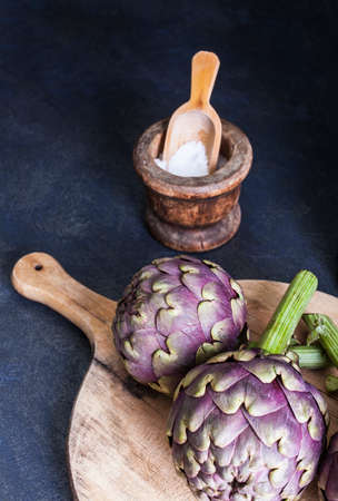 Close up of fresh artichokens on wooden cutting boardの写真素材