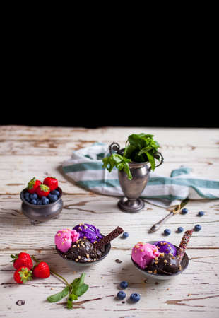Variety of ice cream scoops in the bowls. Chocolate, strawberry and blueberry flavoursの写真素材