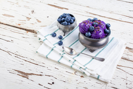Fresh blueberry ice cream inside a pewter cup on old white wooden table