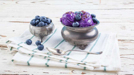 Fresh blueberry ice cream inside a pewter cup on old white wooden tableの写真素材