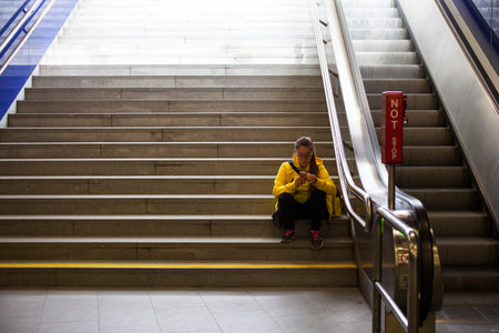 VIENNA, AUSTRIA - MAY, 22: Girl sitting in the subway staircase using a mobile phone on May 22, 2018のeditorial素材