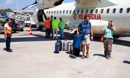 CATANIA AIRPORT, ITALY - AUGUST, 06: Passengers with luggage next to the Airplane  just landed on...