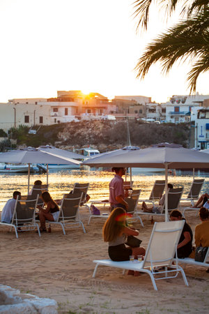 LAMPEDUSA, ITALY - AUGUST, 01: People sitting in deck chairs in the beach bar at the sunset on August 01, 2018のeditorial素材