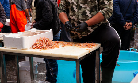 Salesman cleaning the shrimps in  the Catania street fish market 2019