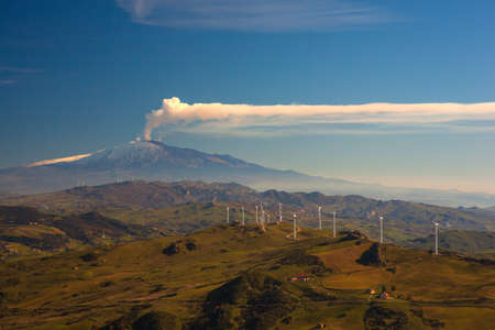 View of windmills and the mount Etna Volcano with smoke. Sicilyの写真素材