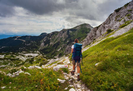 Young woman with backpack hiking along the path in the scenic Vogel mountain part of southern Julian Alps and Triglav National Park heritage of Sloveniaの写真素材