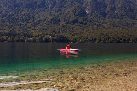 Girl kayaking in the scenik Bohinj lake, Slovenia