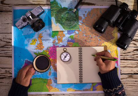 Flat lay of the travel planning concept. Top view of a diary, binoculars, compass, retro photo...