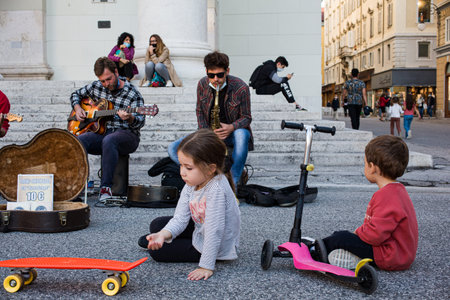 Trieste, Italy - October, 08: Rear view of children looking at street musician performing In the city on October 08, 2020のeditorial素材