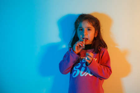 Portrait of a child eating a snack high protein bar on colorful backgroundの写真素材